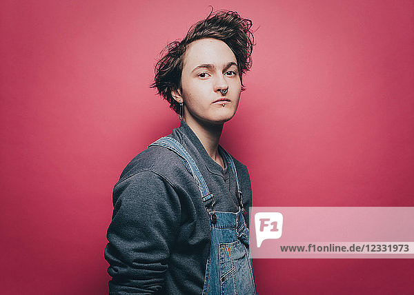 Portrait of confident male hipster standing against pink background