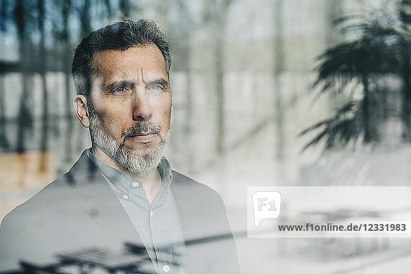 Close-up of thoughtful businessman seen through glass window at office