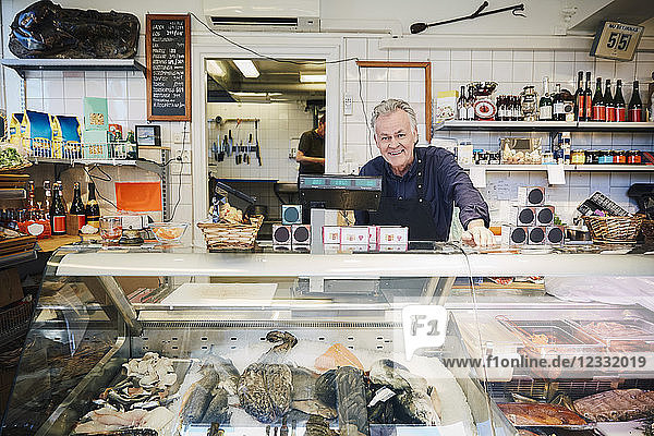Portrait of smiling male owner standing at counter in store