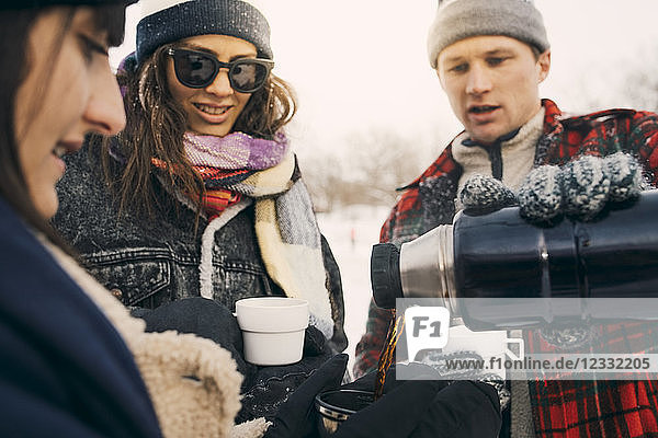 Man serving coffee to friend from insulated drink container