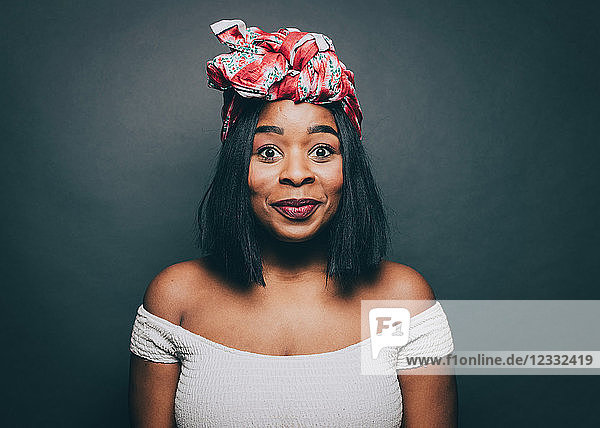 Portrait of excited woman wearing head tie over gray background