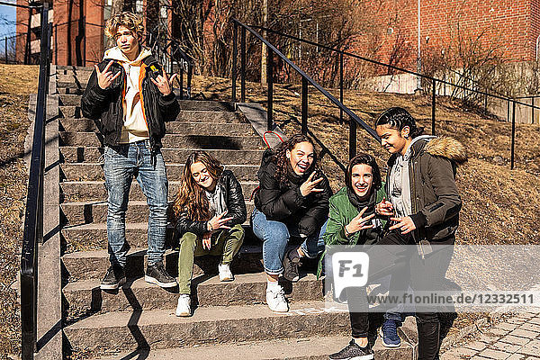 Cheerful multi-ethnic teenage friends gesturing on steps in city