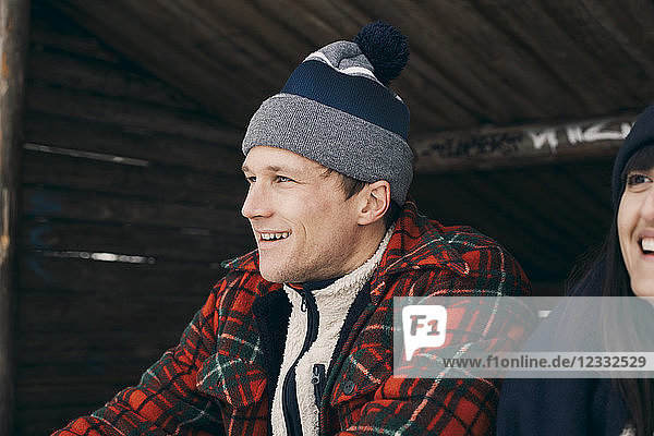 Close-up of smiling man and woman sitting in log cabin