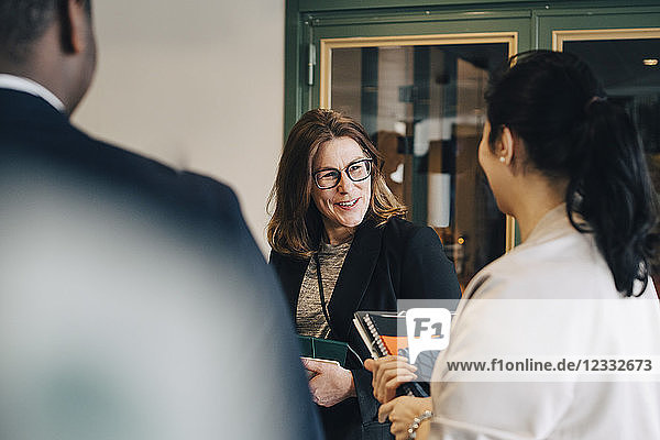 Smiling businesswoman discussing with colleagues at office