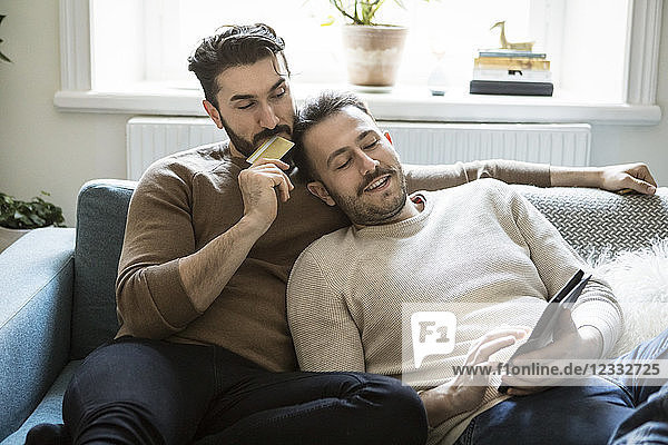 High angle view of homosexual couple doing online shopping while relaxing on sofa at home