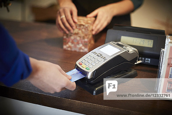 Cropped image of customer paying through credit card at checkout counter