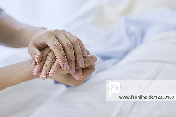 Halten der Hand eines Patienten im Bett