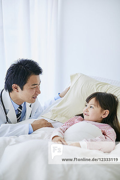 Japanischer Arzt mit einem Patienten im Bett