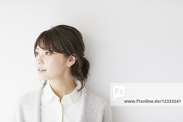 Young Japanese woman against white wall