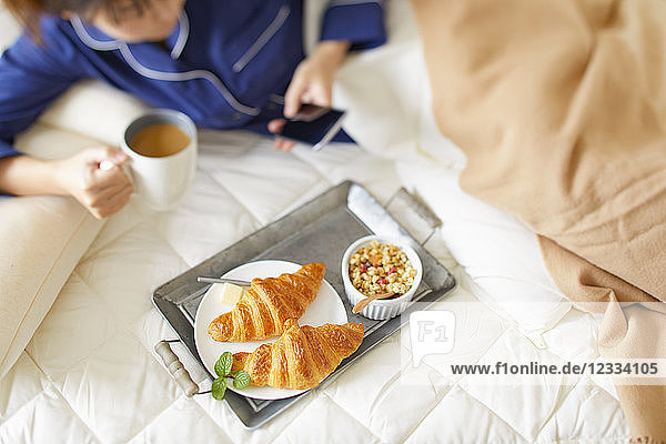 Japanische Frau beim Frühstück im Bett