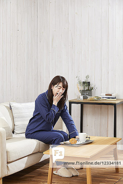 Japanische Frau isst im Pyjama