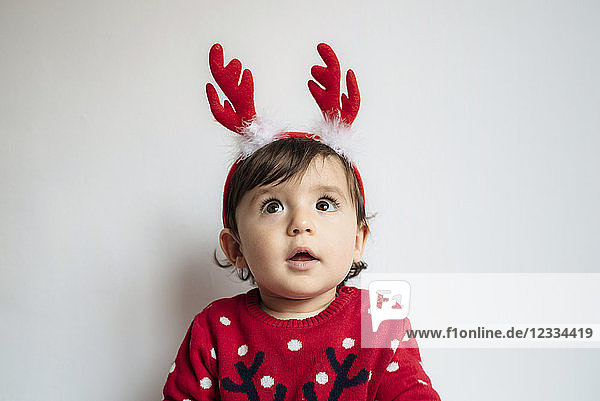 Portrait of astonished baby girl wearing reindeer antlers headband