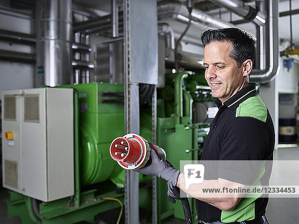 Combined heat and power plant  worker holding high current plug