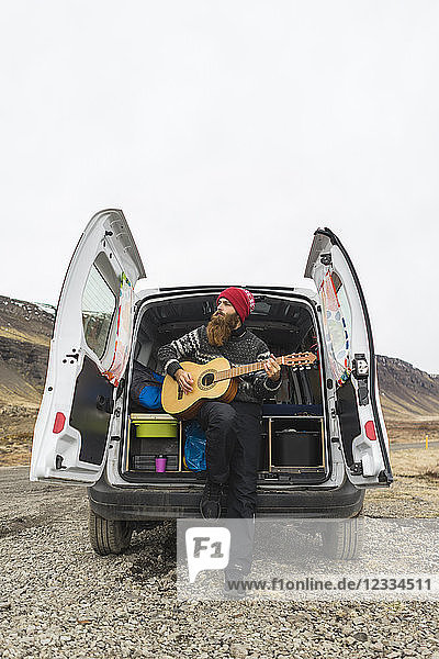 Iceland  man in front of van playing guitar