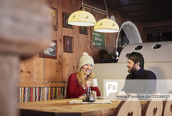 Happy couple drinking hot drink in rustic mountain hut