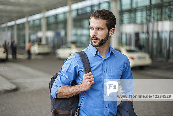 Young businessman with backpack on the go