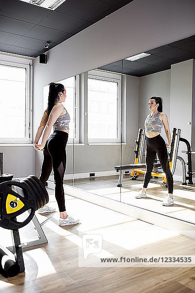 Woman exercising in gym looking in mirror