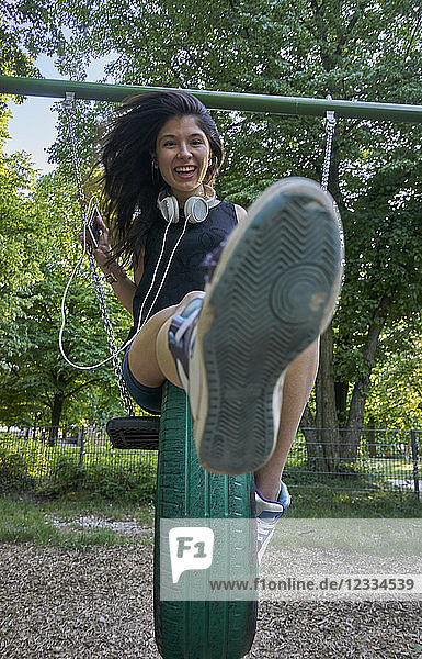 Portrait of happy young woman on a swing