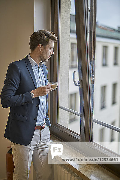 Businessman with cup of coffee looking out of window