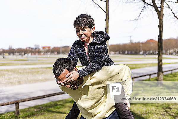 Happy father carrying son piggyback in a park