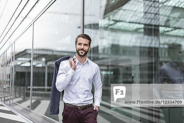Portrait of smiling young businessman at glass facade