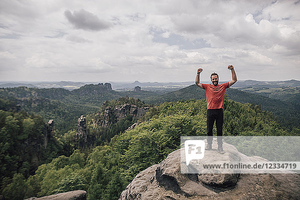 Germany  Saxony  Elbe Sandstone Mountains  man on a hiking trip standing on rock cheering