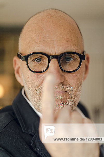 Senior man with glasses  focussing on his index finger