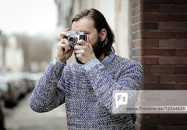 Man with beard taking pictures with old camera