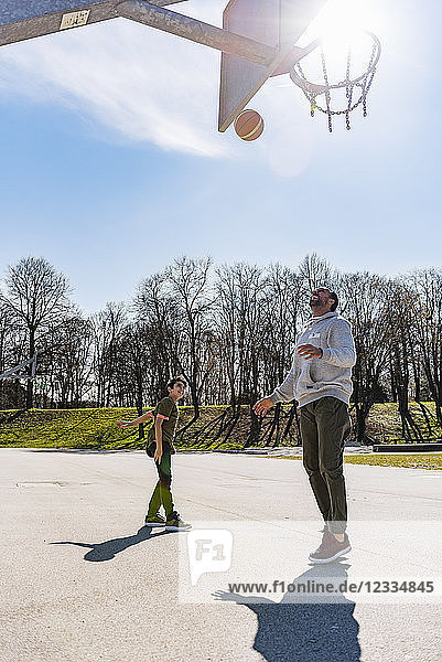 Father and son playing basketball on court outdoors