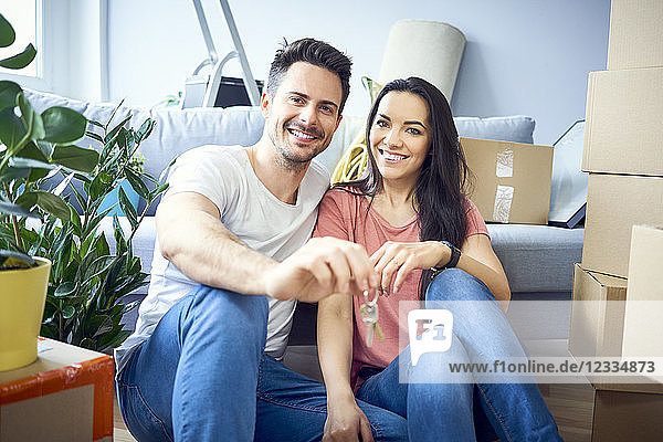 Portrait of happy couple moving in showing keys to new apartment
