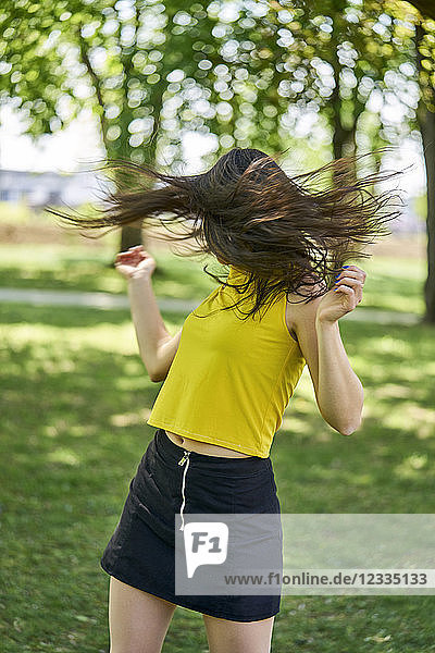 Young woman in park tossing her hair