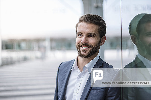 Portrait of smiling young businessman at glass facade