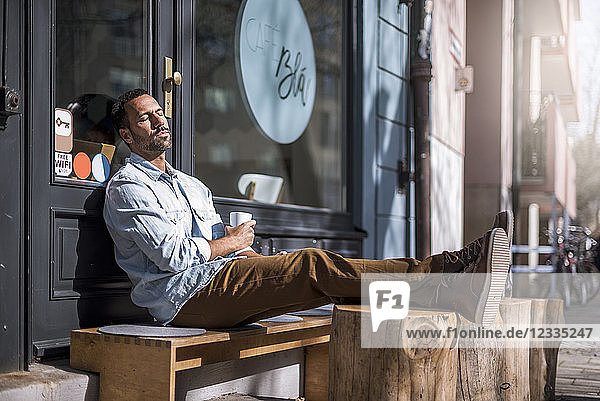 Relaxed man sitting outside a cafe enjoying the sunshine