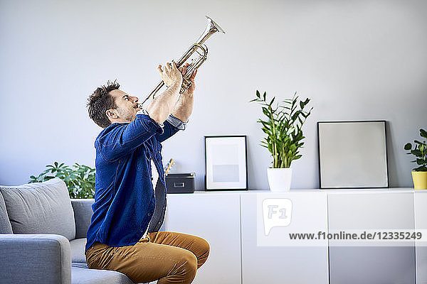 Man sitting on couch playing trumpet