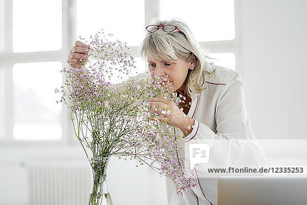 Mature woman with laptop caring for flowers