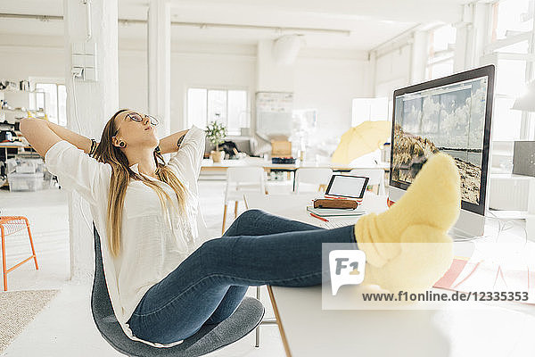 Young freelancer relaxing with feet up at desk in a loft