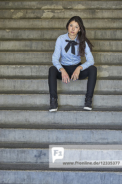 Portrait of fashionable young businesswoman sitting on stairs