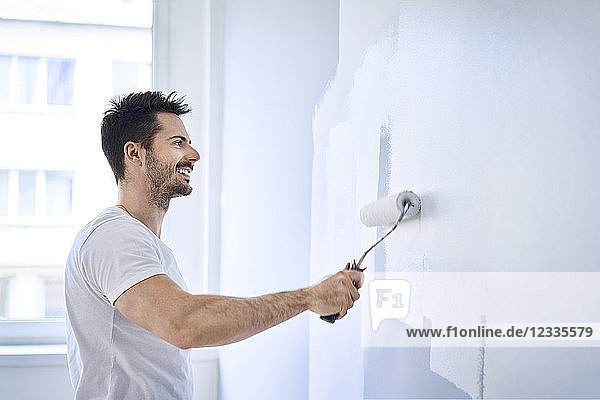 Smiling man painting wall in apartment