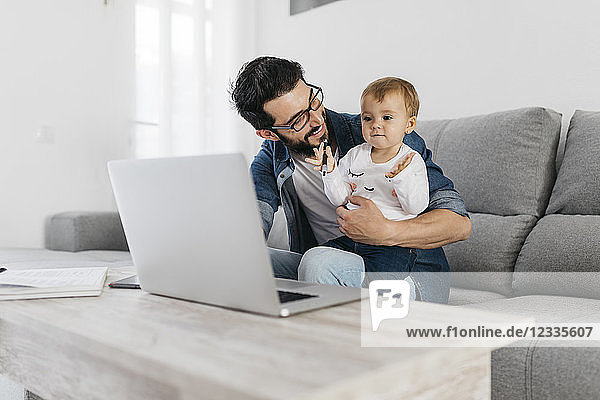 Father and daughter using laptop at home