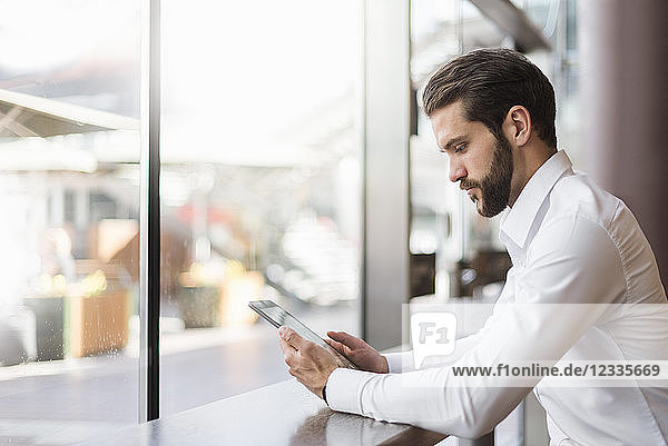 Young businessman using tablet in a cafe at the window