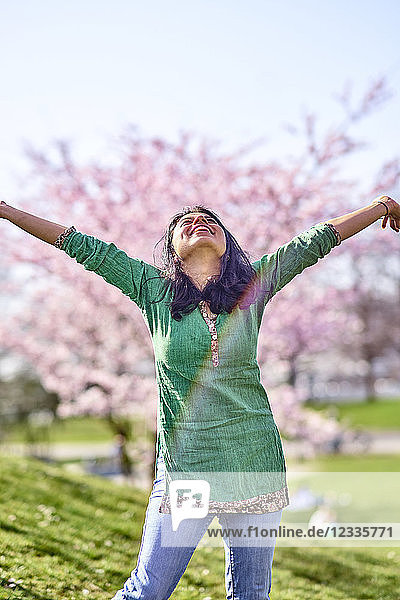 Happy young woman in a park at cherry blossom tree