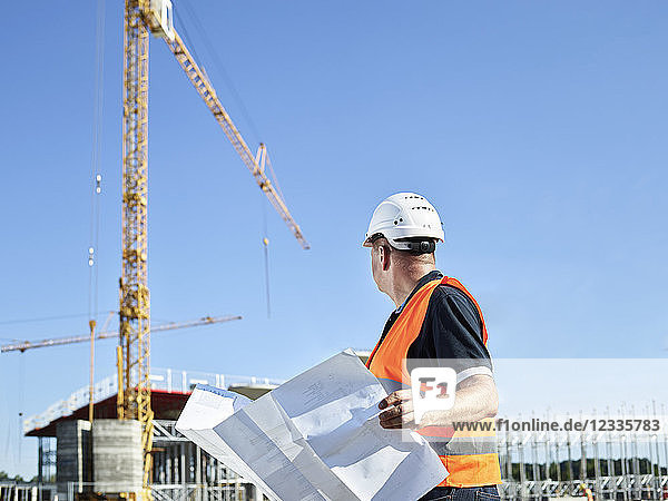 Construction worker with blueprint on construction site