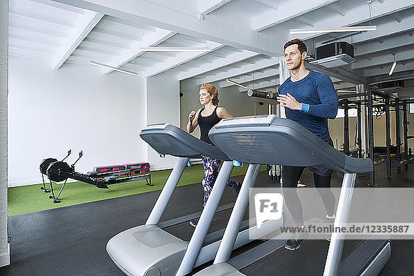 Man and woman running on treadmill at gym