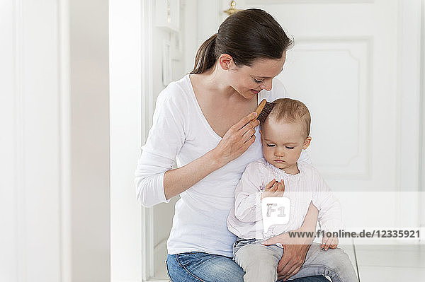 Mother brushing baby's hair at home
