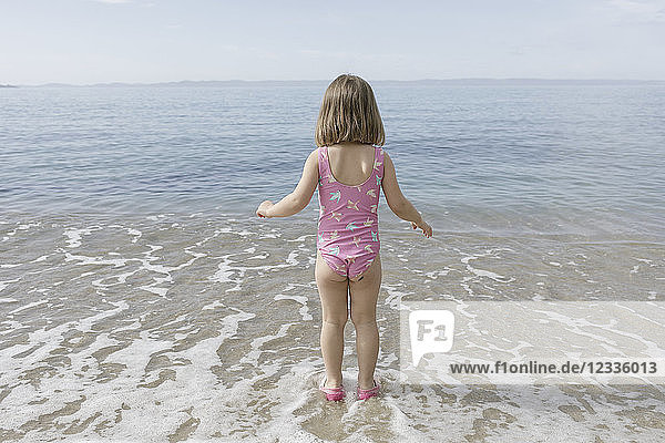 Back view of little girl standing at seafront