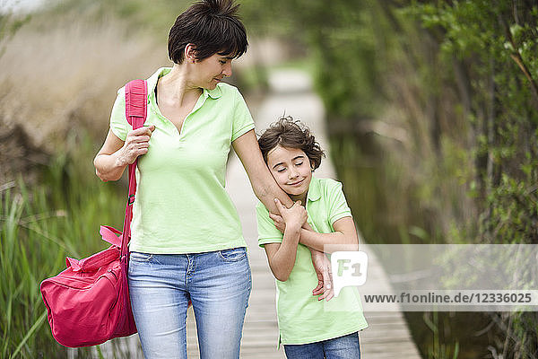 Mother and affectionate daughter walking on boardwalk