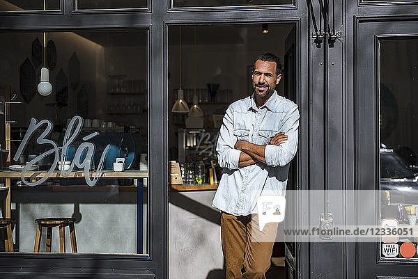 Smiling man standing at entrance door of a cafe