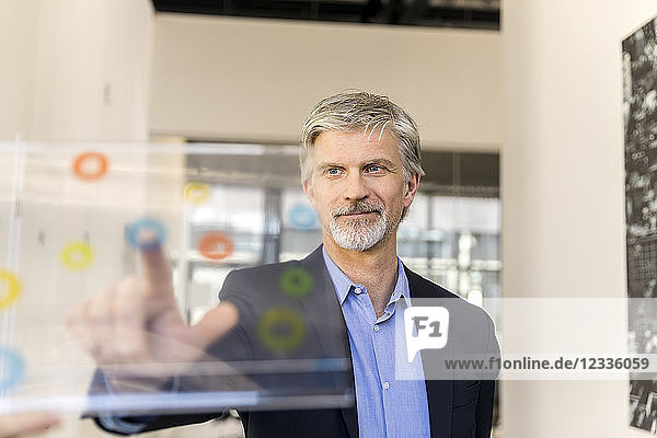 Mature businessman using transparent touchscreen computer