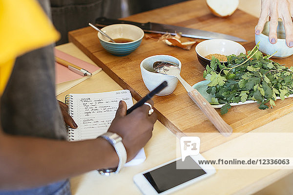 Close-up of woman taking notes in a cooking workshop