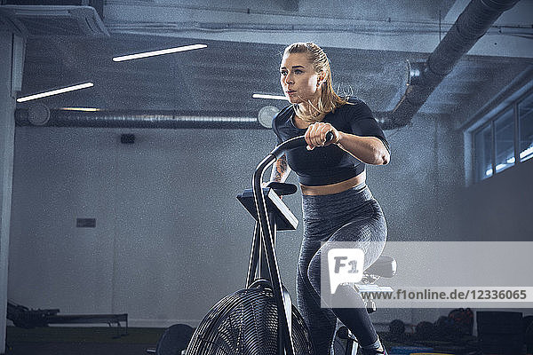 Athletic woman doing airbike workout at gym